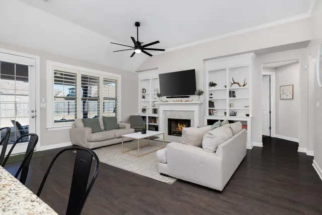 a living room with furniture a fireplace a flat screen tv and a large window