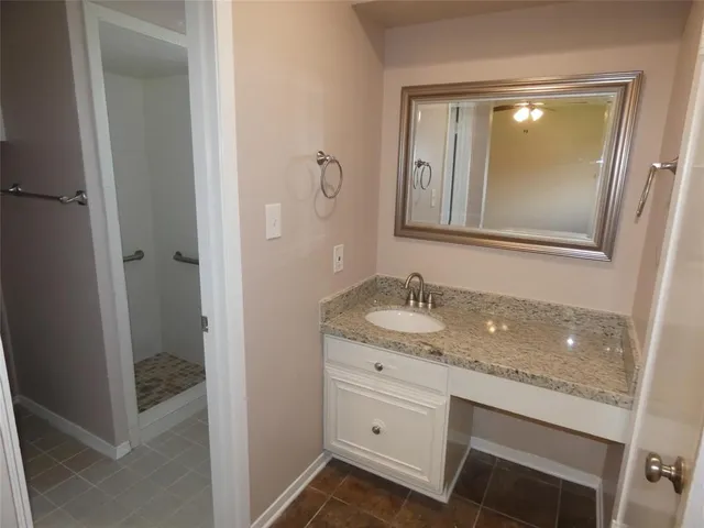 a bathroom with a granite countertop sink and mirror with toilet