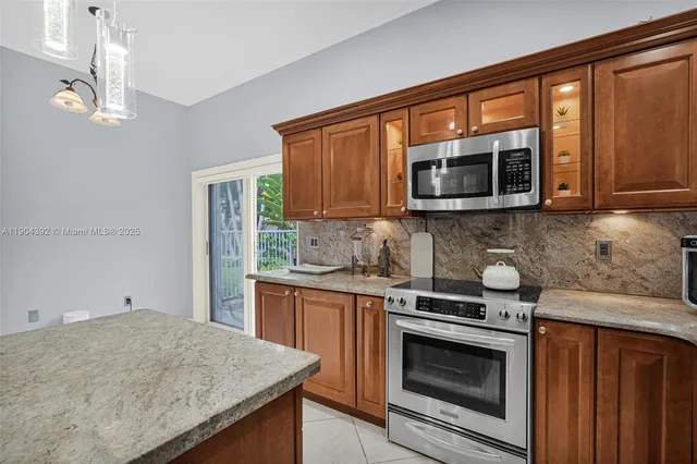 a kitchen with stainless steel appliances granite countertop a sink stove microwave and refrigerator