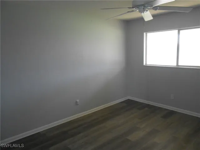 an empty room with wooden floor and fan