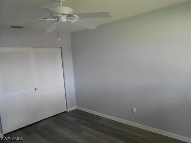 an empty room with a ceiling fan and wooden floor