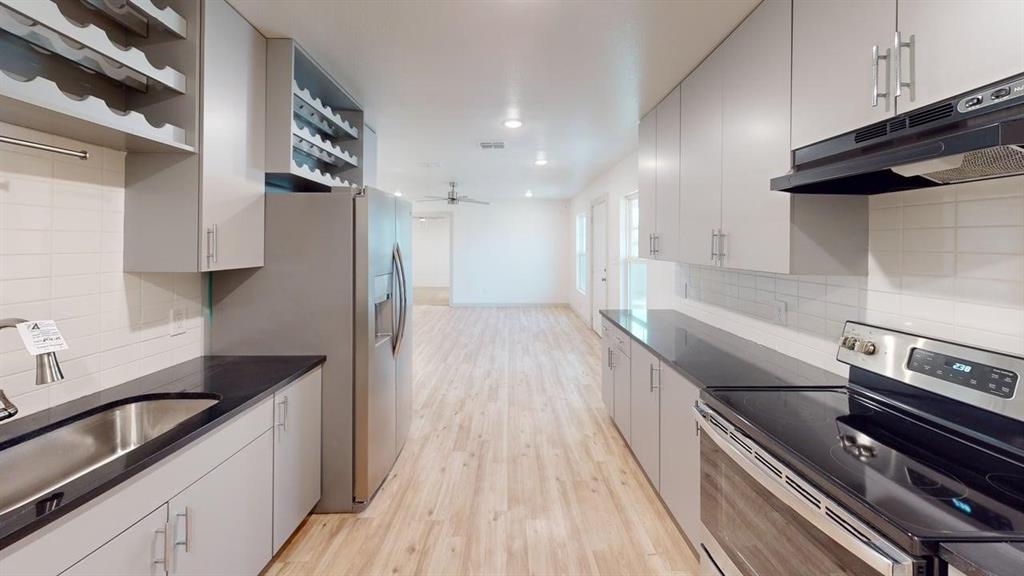 2554 Marfa Avenue Dallas, TX 75216 - Photo 6 of 19 Kitchen with stainless steel appliances, light wood-style floors, open shelves, tasteful backsplash, and a ceiling fan