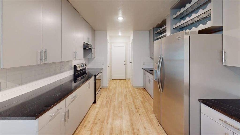 2554 Marfa Avenue Dallas, TX 75216 - Photo 7 of 19 Kitchen with stainless steel appliances, open shelves, light wood-style floors, dark stone counters, and recessed lighting