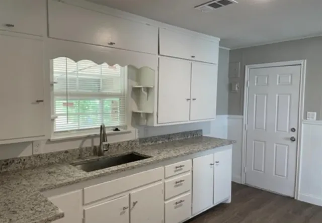 a kitchen with granite countertop a sink and white cabinets
