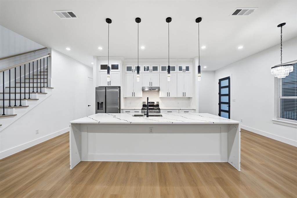 306 East 7th Street Dallas, TX 75203 - Photo 8 of 22 Expansive kitchen island with a waterfall countertop, accented by four pendant lights