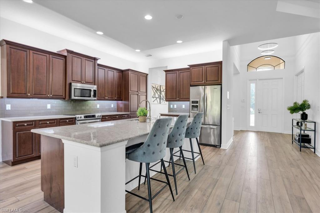 3376 Atlantic Circle Naples, FL 34119 - Photo 9 of 23 a kitchen with stainless steel appliances granite countertop a refrigerator a stove top oven a sink dishwasher and wooden cabinets with wooden floor