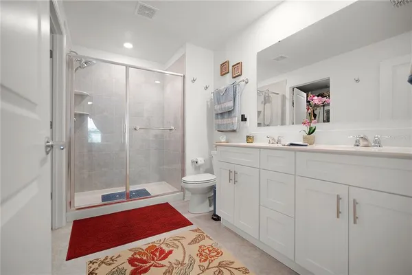 a spacious bathroom with a double vanity sink toilet mirror and shower