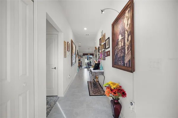a hallway with painting on the wall and a potted plant