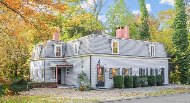 a view of a white house with large windows and a tree