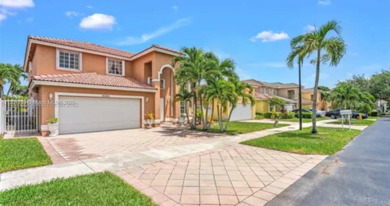 16461 Southwest 100th Terrace Miami, FL 33196 - Photo 2 of 18 a front view of a house with a garden and palm trees