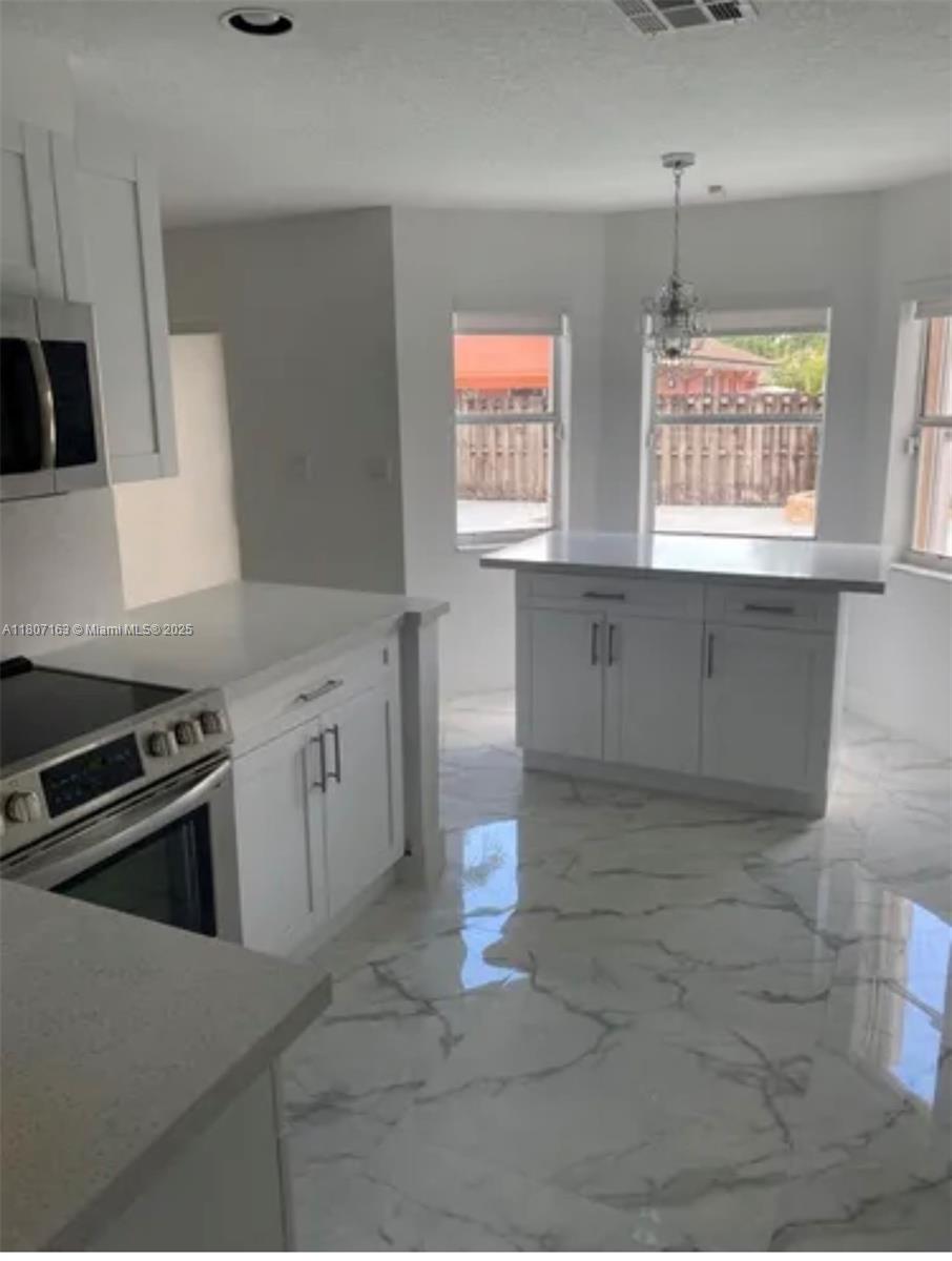 16461 Southwest 100th Terrace Miami, FL 33196 - Photo 6 of 18 a kitchen with stainless steel appliances a stove a sink a microwave a window and cabinets