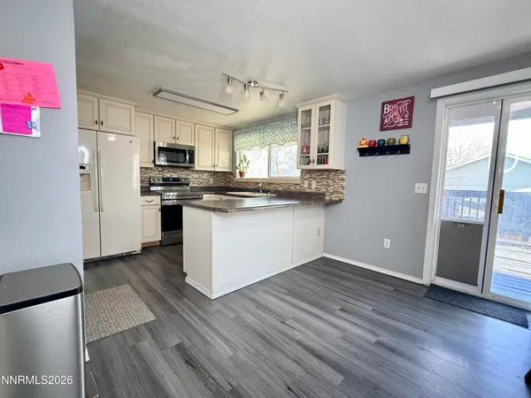 a kitchen with stainless steel appliances granite countertop a refrigerator a stove top oven a sink and dishwasher with wooden floor