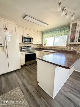 a kitchen with stainless steel appliances granite countertop a stove a sink dishwasher a refrigerator and a microwave oven with wooden floor