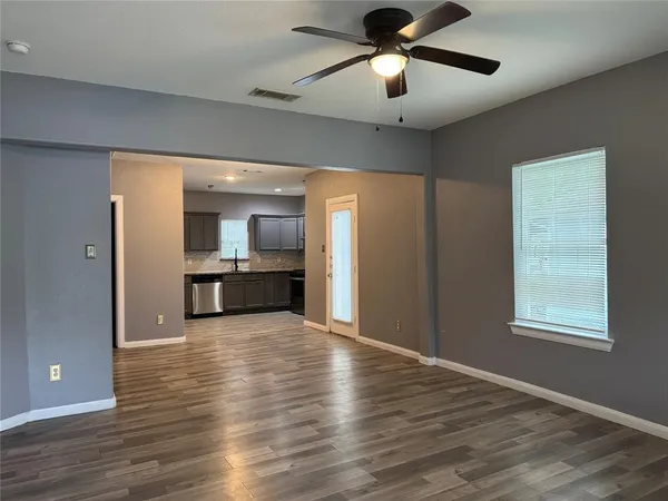 a view of an empty room with a window and wooden floor
