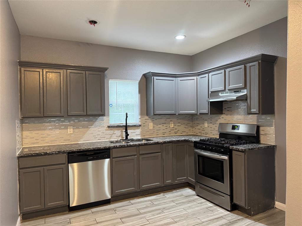 7315 Toland Street Dallas, TX 75227 - Photo 7 of 16 a kitchen with granite countertop stainless steel appliances a sink stove and cabinets