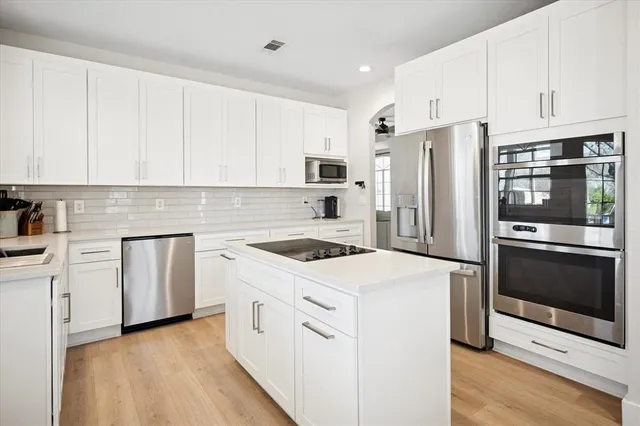 a kitchen with white cabinets and stainless steel appliances