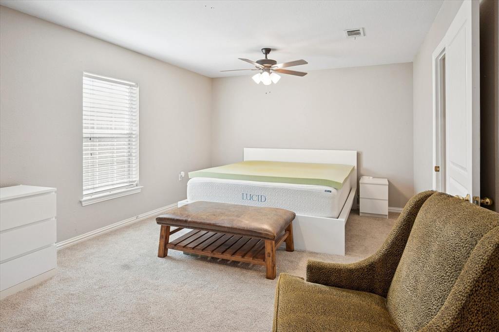 437 South 1st Street Krum, TX 76249 - Photo 33 of 38 a bedroom with a bed and a chandelier