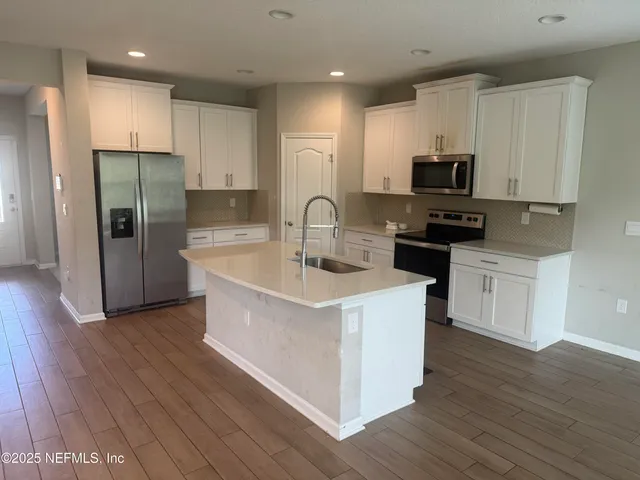 a kitchen with stainless steel appliances a microwave a sink a stove a refrigerator and cabinets