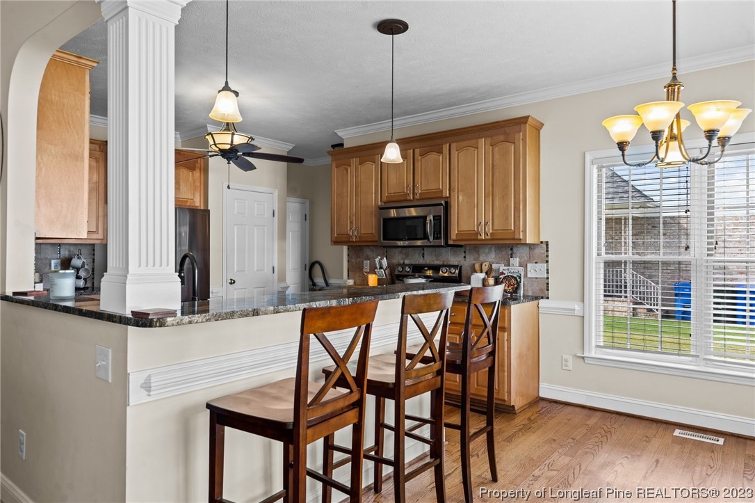 6407 Cattesmore Road Fayetteville, NC 28311 - Photo 16 of 42 a kitchen with stainless steel appliances kitchen island granite countertop a stove a sink and a microwave