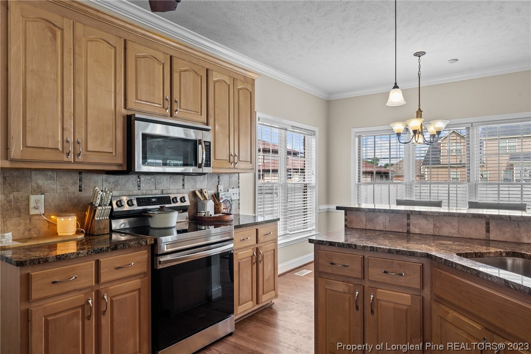 6407 Cattesmore Road Fayetteville, NC 28311 - Photo 18 of 42 a kitchen with stainless steel appliances granite countertop a stove a sink dishwasher and a microwave oven with white cabinets