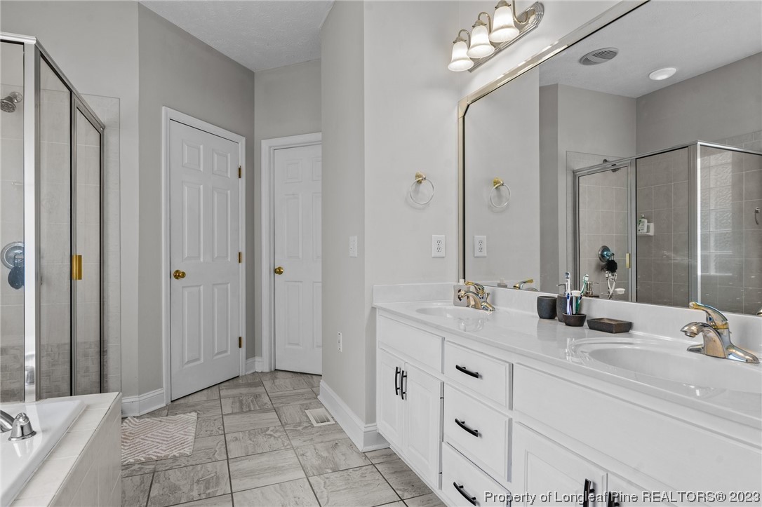 6407 Cattesmore Road Fayetteville, NC 28311 - Photo 6 of 42 a bathroom with double vanity sinks a vanity a mirror and a shower