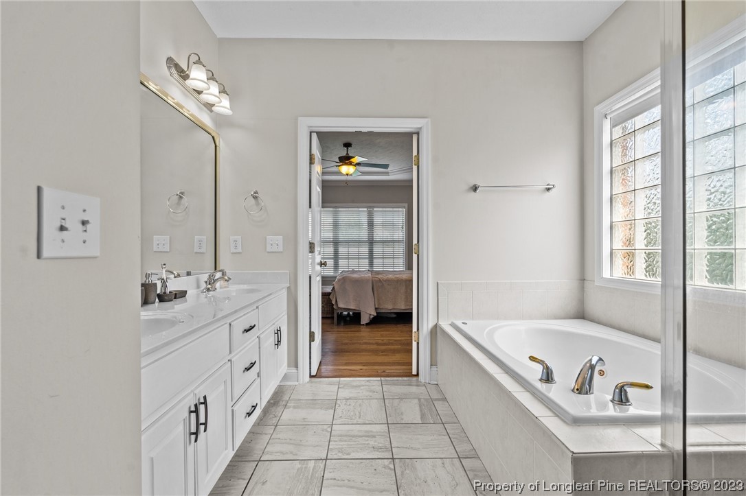 6407 Cattesmore Road Fayetteville, NC 28311 - Photo 7 of 42 a bathroom with a tub a double vanity sink and mirror