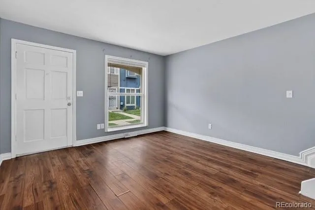 a view of an empty room with wooden floor and a window