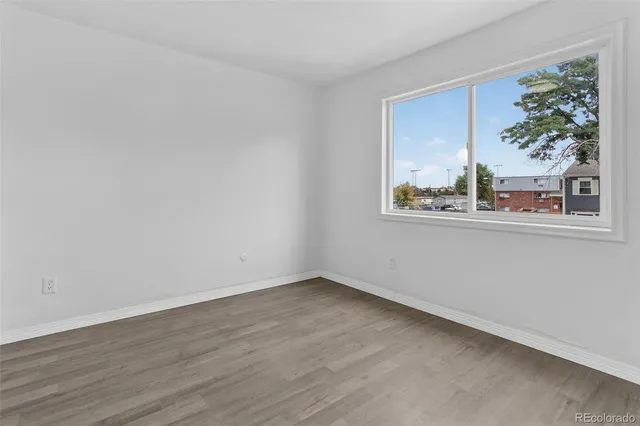 a view of an empty room with wooden floor and closet