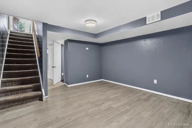 an empty room with wooden floor and stairs