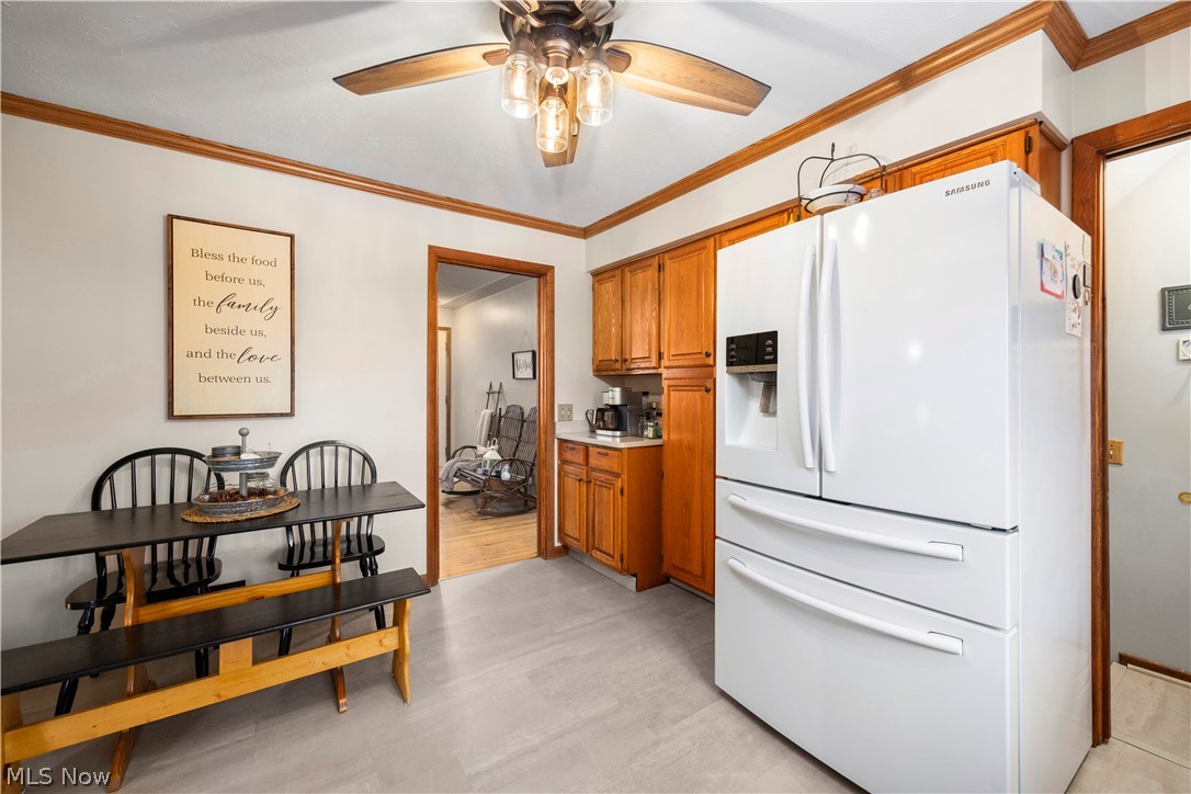 965 Gulf Road Elyria, OH 44035 - Photo 10 of 37 Kitchen with white fridge with ice dispenser, wood cabinetry, ornamental molding, light countertops, and ceiling fan