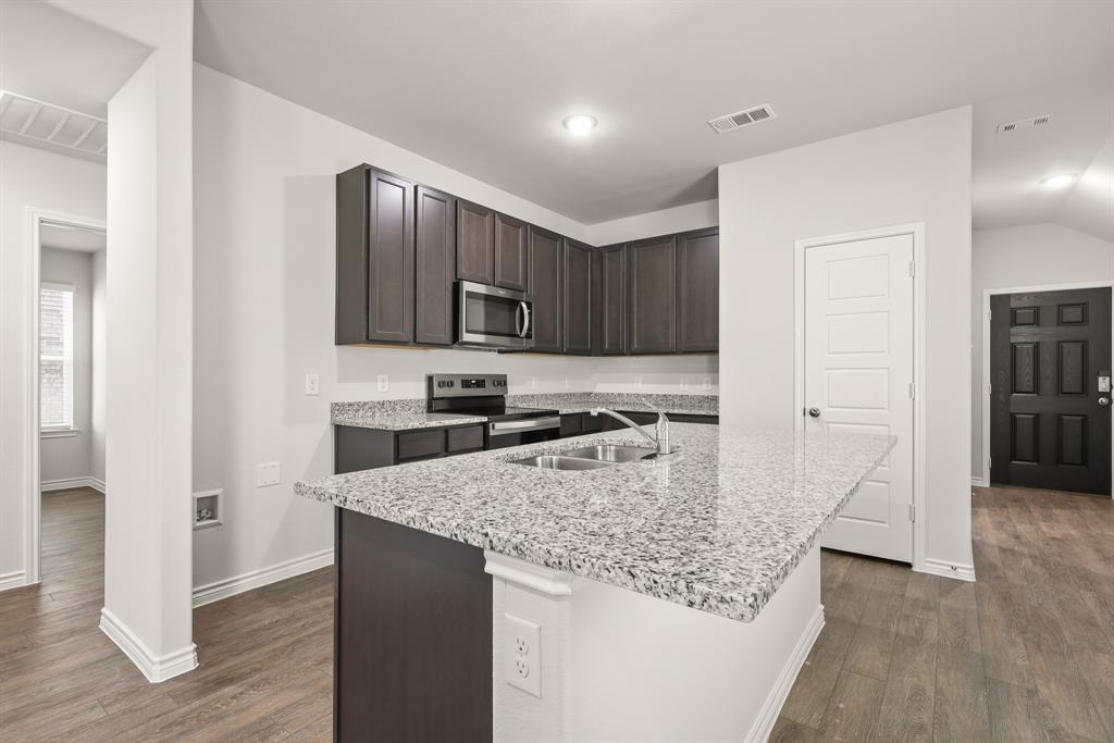 1508 Romans Road Ennis, TX 75119 - Photo 4 of 19 a kitchen with kitchen island granite countertop wooden cabinets a sink and a stove