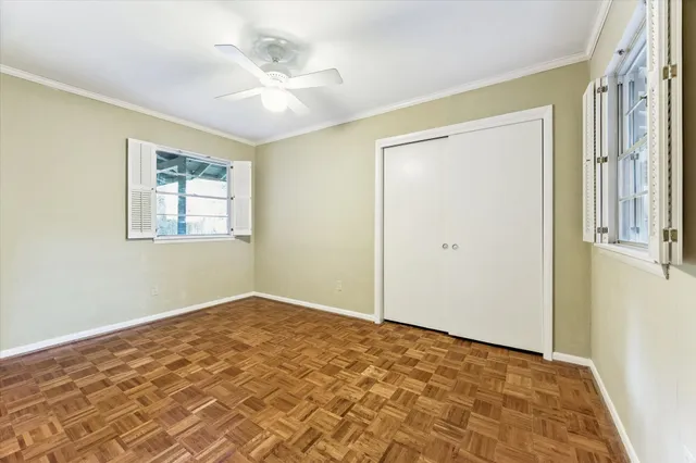 a view of a bedroom with wooden floor and a ceiling fan