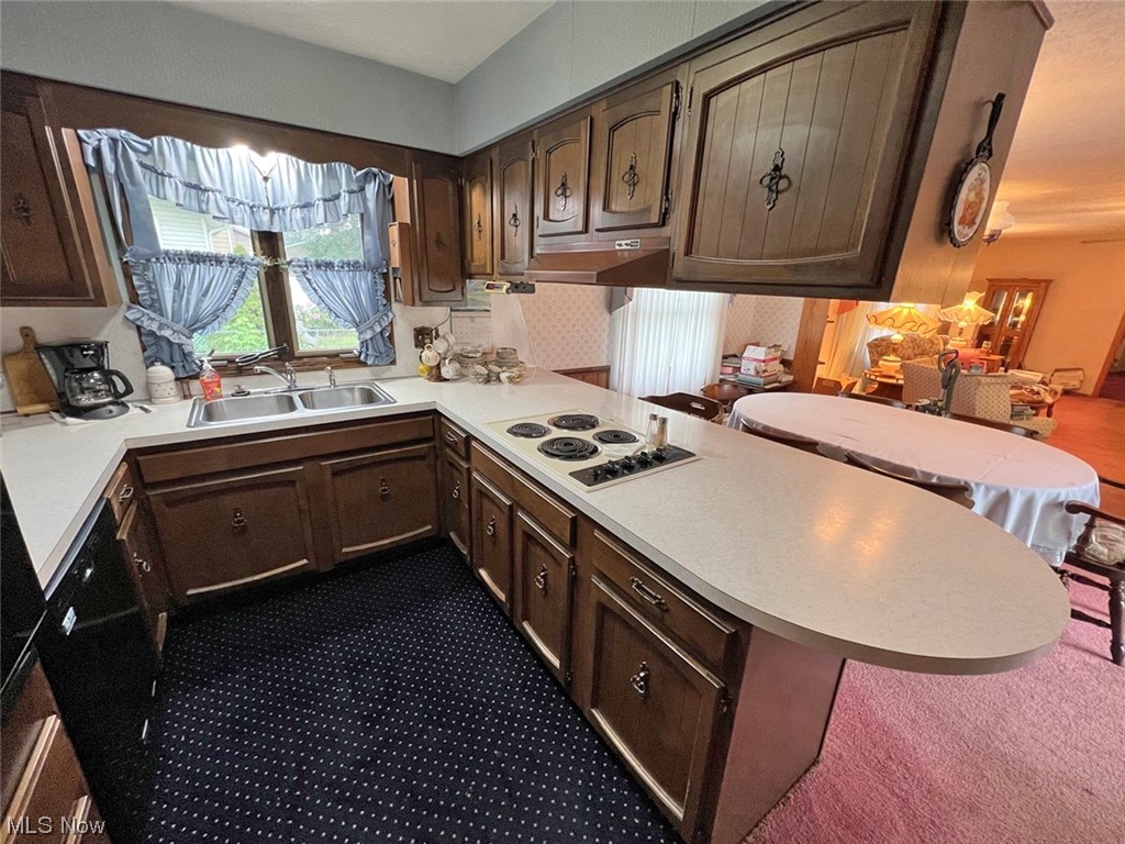 918 Amherst Road Northeast Massillon, OH 44646 - Photo 9 of 31 Kitchen featuring kitchen peninsula, white electric cooktop, dark brown cabinets, dark colored carpet, and sink