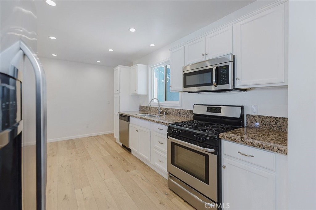 17134 Sherman Way Lake Balboa, CA 91406 - Photo 15 of 27 a kitchen with stainless steel appliances granite countertop a stove a microwave and a refrigerator