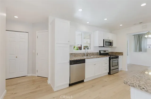 a kitchen with granite countertop white cabinets and stainless steel appliances