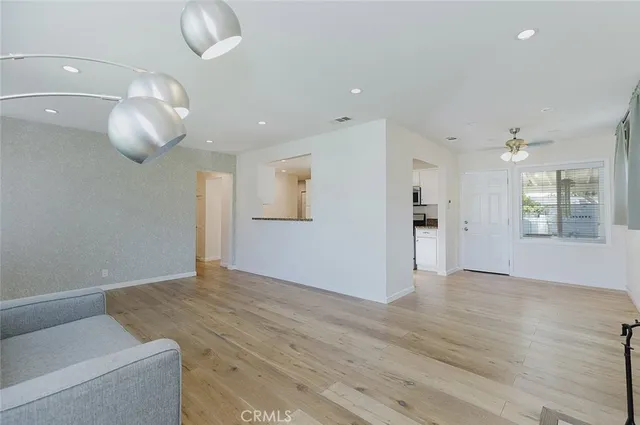 a view of an empty room with wooden floor and a window