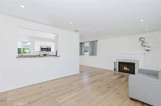 a living room with stainless steel appliances furniture a fireplace and wooden floor