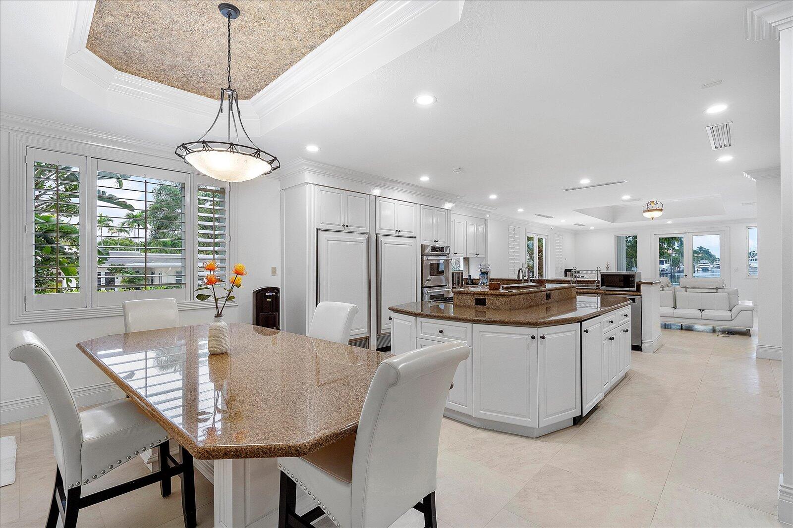 414 Riviera Isle Drive Fort Lauderdale, FL 33301 - Photo 27 of 70 a kitchen with stainless steel appliances granite countertop a dining table chairs and a chandelier