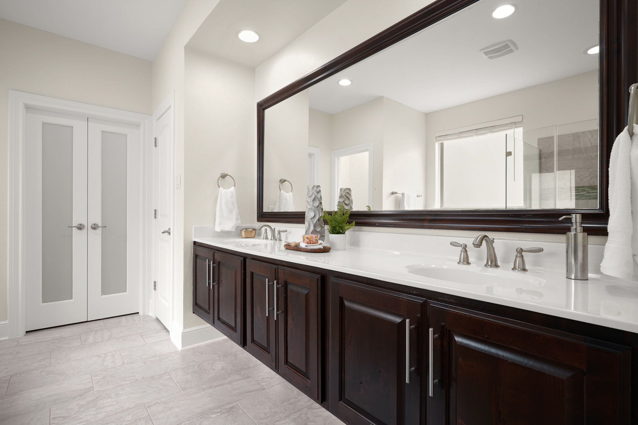440 Cherokee Rose Circle Georgetown, TX 78626 - Photo 27 of 39 A refined bathroom featuring a long, dark wood vanity with dual sinks and a grand mirror, complemented by frosted glass doors.