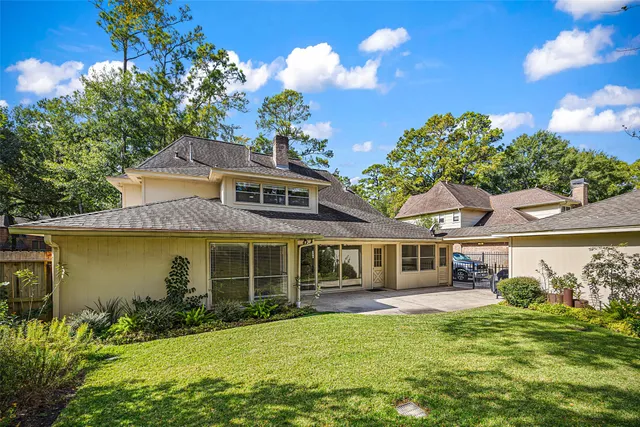 an aerial view of a house with swimming pool and large trees