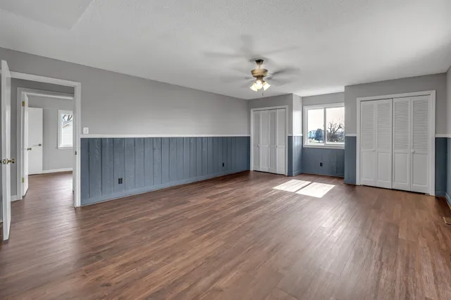 an empty room with wooden floor and ceiling fan