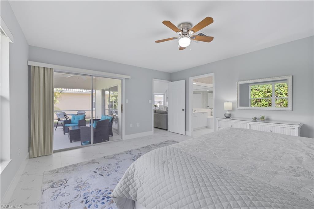 3605 Corinthian Way Naples, FL 34105 - Photo 9 of 33 a spacious bedroom with a large bed a chandelier and windows