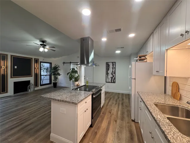 a kitchen with stainless steel appliances granite countertop a sink a stove and a wooden floors