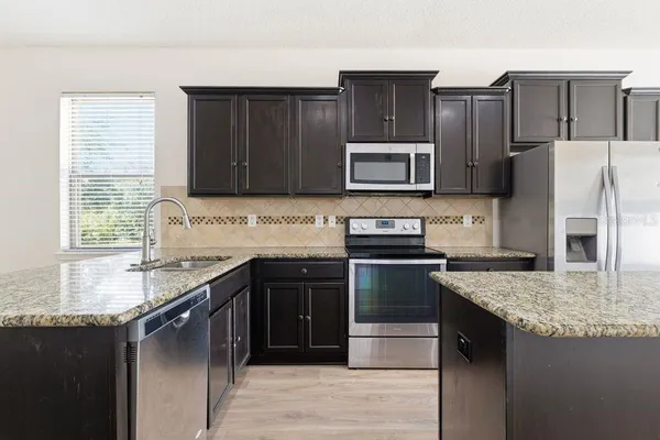 a kitchen with stainless steel appliances granite countertop a refrigerator a stove top oven a sink and dishwasher