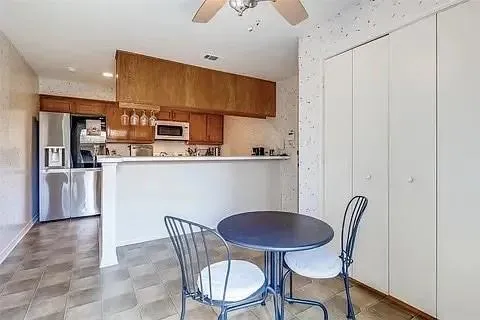 a kitchen with stainless steel appliances granite countertop a dining table chairs and a refrigerator