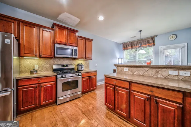 a kitchen with stainless steel appliances granite countertop wooden cabinets a stove top oven a sink and dishwasher