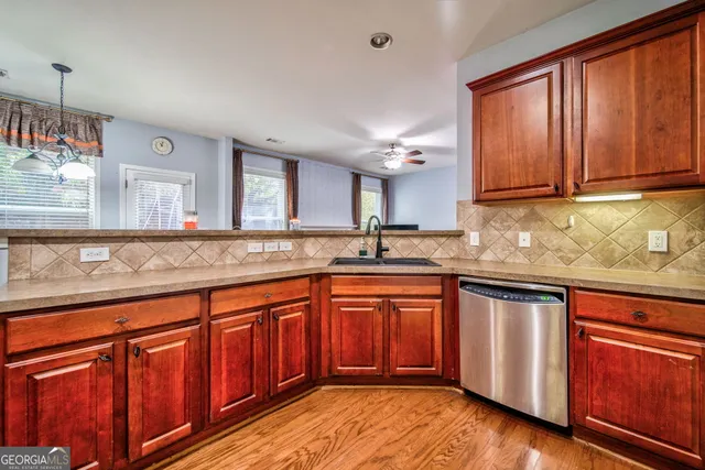 a kitchen with stainless steel appliances granite countertop wooden cabinets a sink and dishwasher with wooden floor