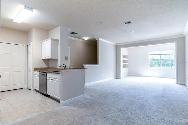 a view of a kitchen with a sink and dishwasher a refrigerator with white cabinets