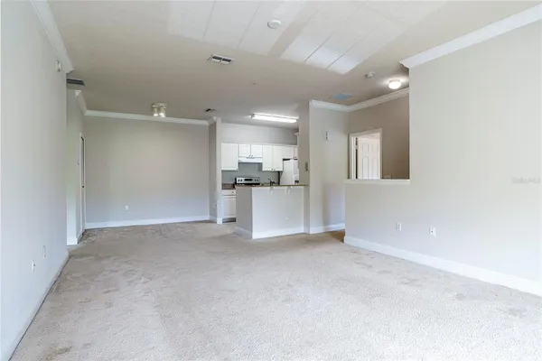 an empty room with a kitchen and a refrigerator