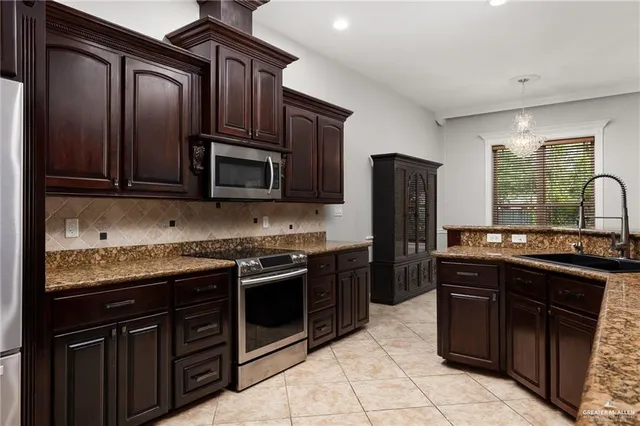 a kitchen with stainless steel appliances granite countertop a stove top oven microwave and refrigerator